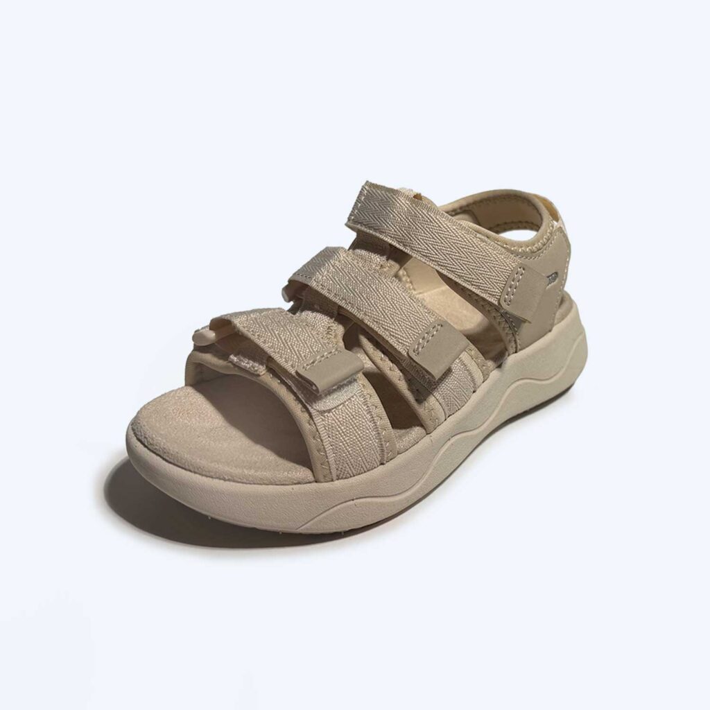 Beige sandal with three adjustable Velcro straps and a thick, contoured sole, displayed on a plain light background.
