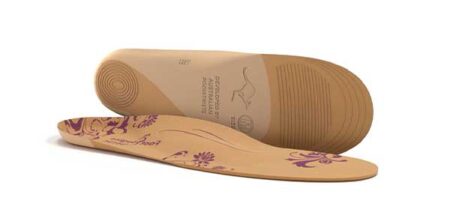 Two tan orthopedic shoe insoles with purple floral designs are shown, one lying flat and the other standing to display the textured sole and arch support.