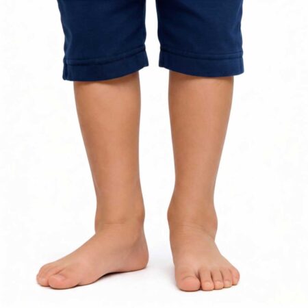 A child standing barefoot on a white background, wearing blue rolled-up pants.